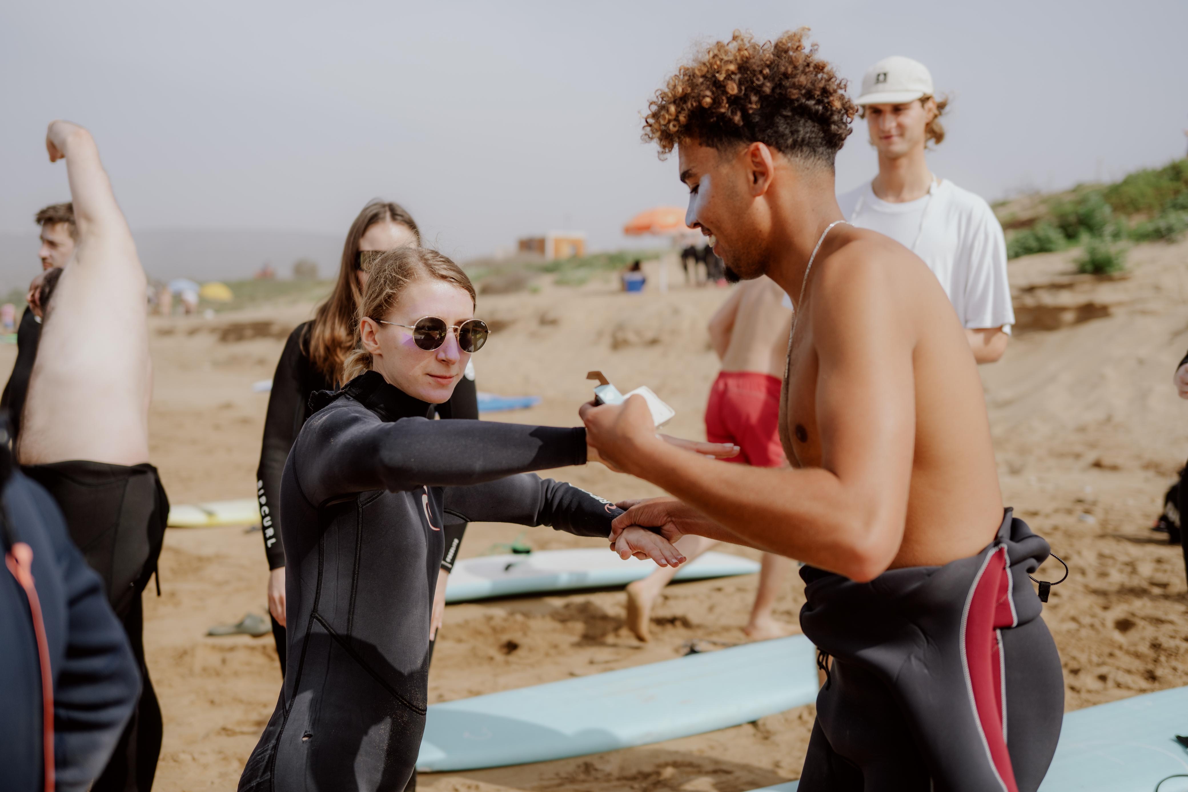 Surf Freaks Morocco coach helping a student with her wetsuit before a session on the Taghazout coast