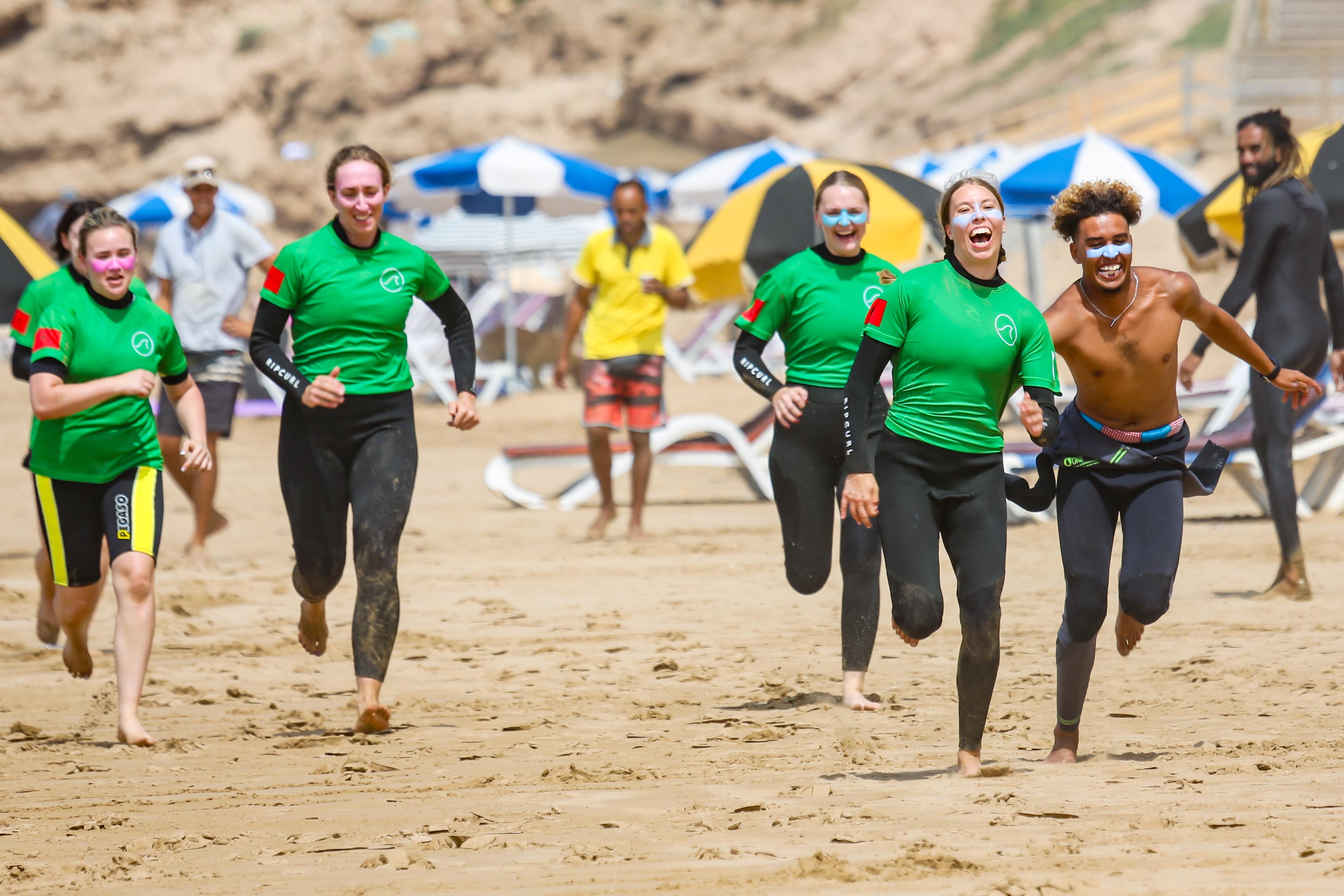 A stoked group running up the beach together after a session